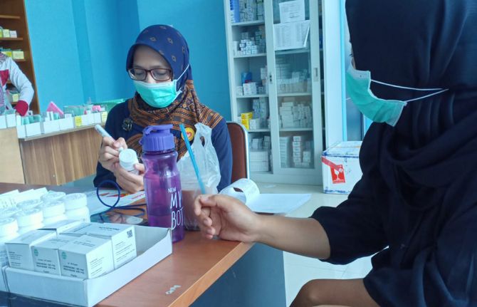 An outreach worker taking antiretroviral therapy for a client in the pharmacy.