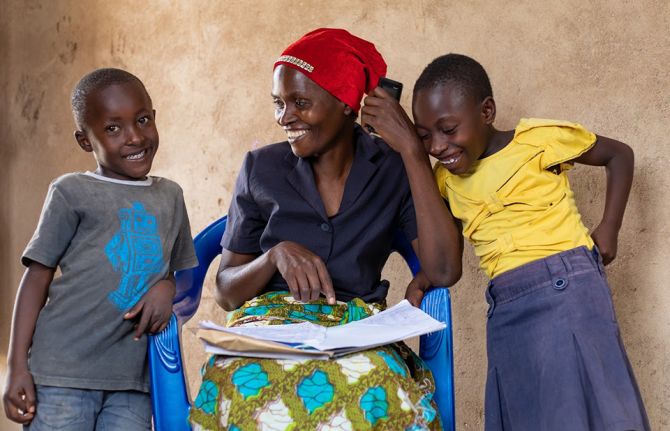 Jema Adamu, a woman living with HIV, and peer educator, helping son Jacksomi and grand daughter Faraja with school work.  Nkuhungu, Dodoma, Tanzania, 4 October 2019  Credit: UNAIDS